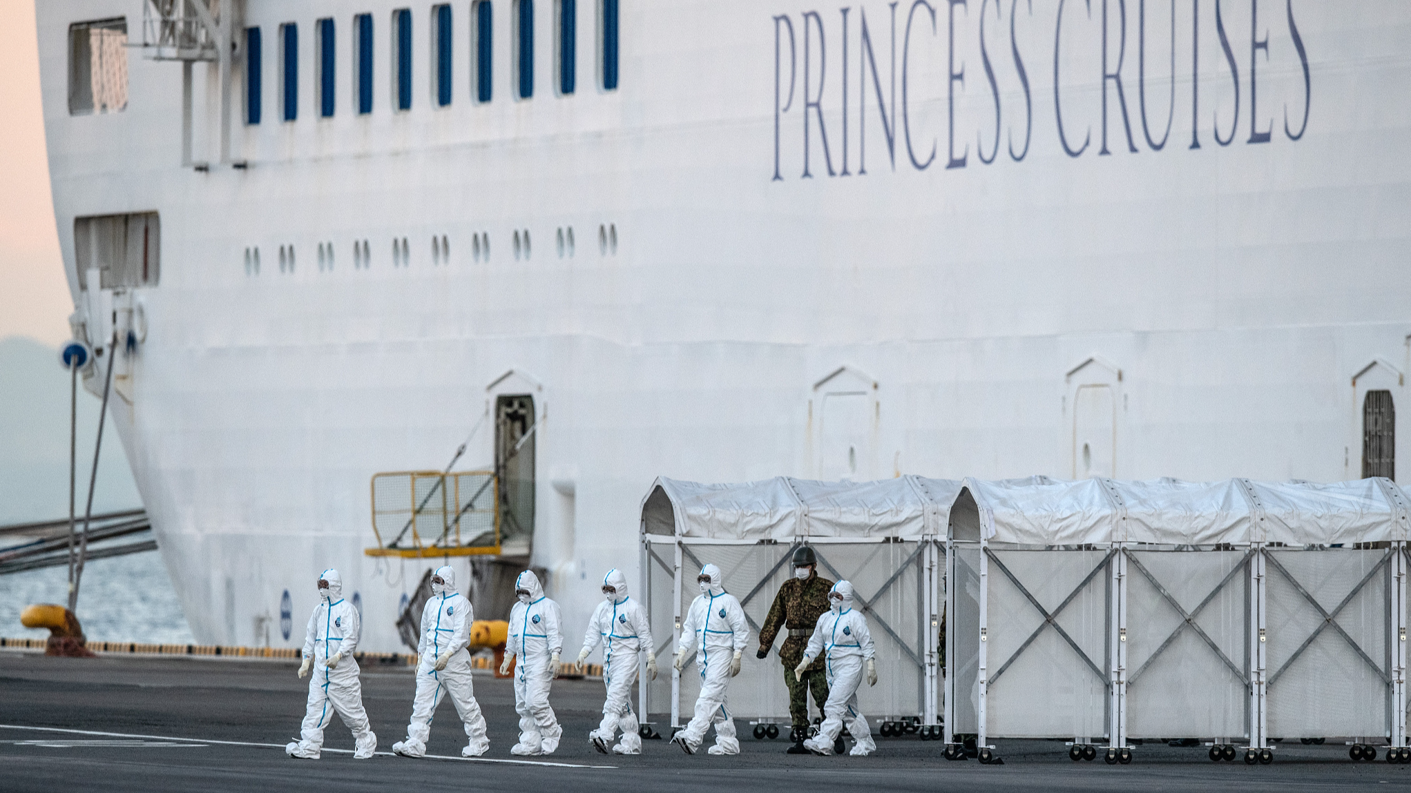 Japanese emergency workers wearing protective clothing walk out of the Diamond Princess cruise ship at Daikoku Pier in Yokohama, Japan, February 17, 2020. /CFP