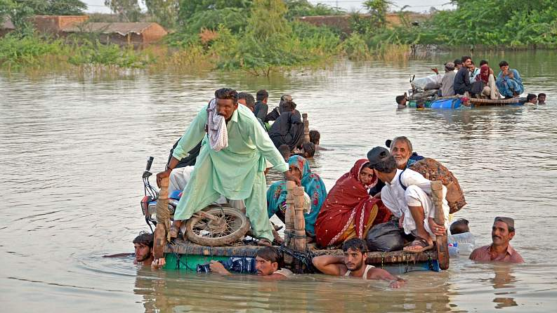 Internally displaced people wade through floodwaters after heavy monsoon rains, Balochistan, Pakistan, September 8, 2022. /CFP