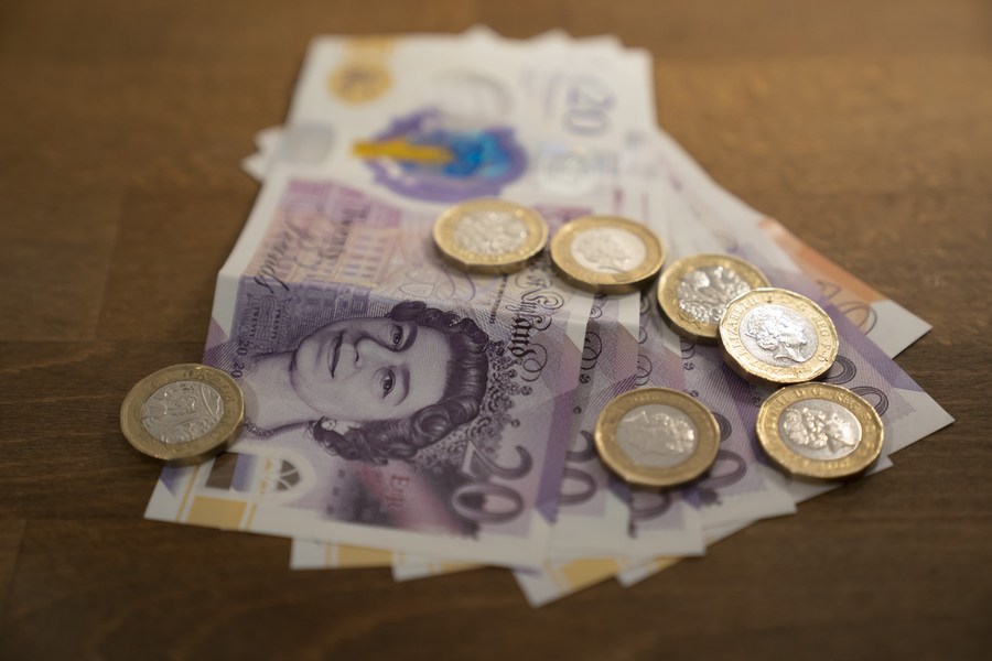 Notes and coins are seen in a family in Manchester, Britain, March 18, 2022. /Xinhua)