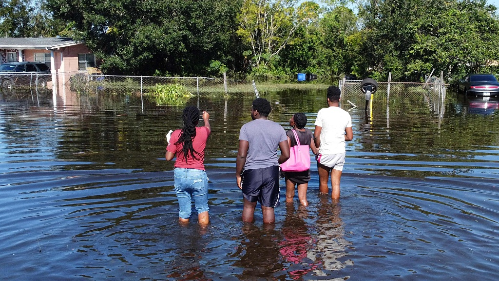 Residents wade through water to get to their house in a flooded neighborhood following Hurricane Ian in Orlando, Florida, October 1, 2022. /CFP