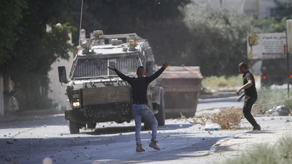 Palestinian protesters throw stones at Israeli army vehicles following a deadly raid in the city of Jenin in the West Bank, September 28, 2022. /CFP