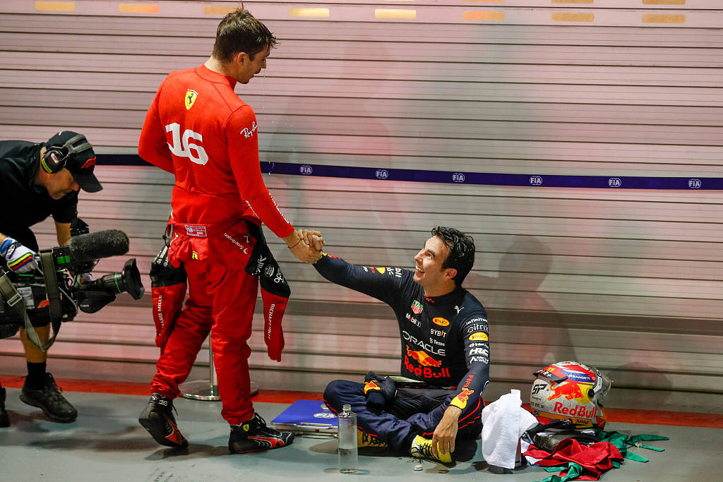 Charles Leclerc (C) of Ferrari shakes hands with winner Sergio Perez (R), who takes a rest after the race, in Singapore, October 2, 2022. /CFP 
