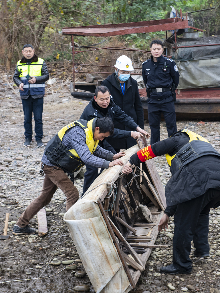 Law enforcement officers and volunteers confiscate an illegal fishing boat in Chongqing Municipality of southwest China on December 31, 2020. /VCG