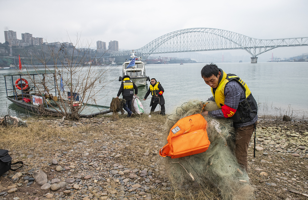 Volunteers clear fishing nets in Chongqing Municipality of southwest China on December 31, 2020. These volunteers were local fishermen before the 10-year fishing ban on the Yangtze River came into effect. /VCG