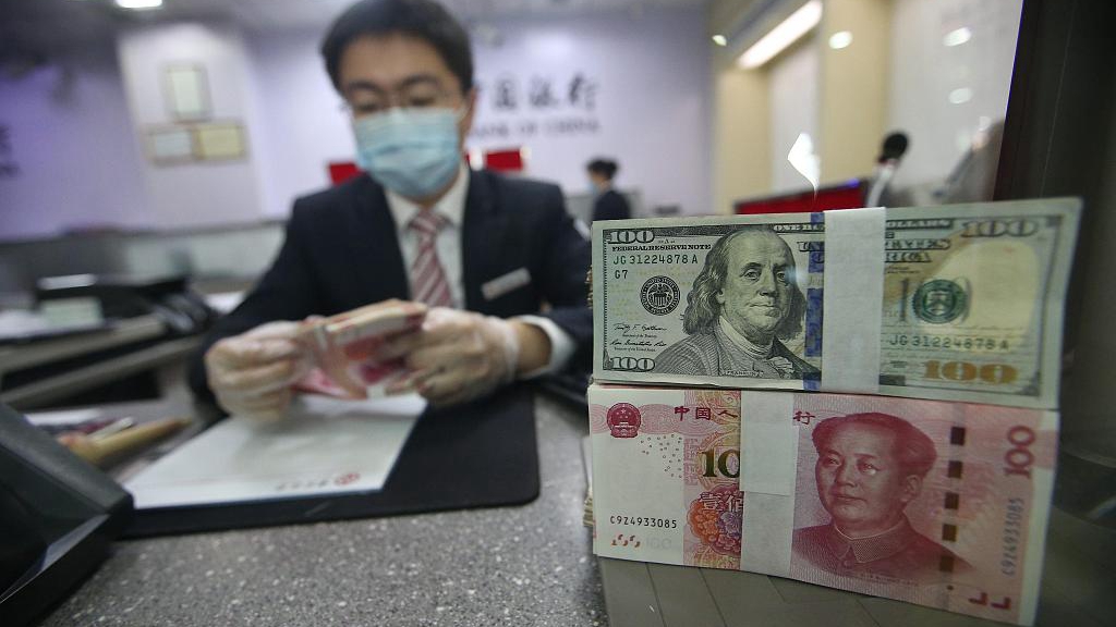 A bank staff counting bank notes in central China's Shanxi Province, March 20, 2020. /CFP