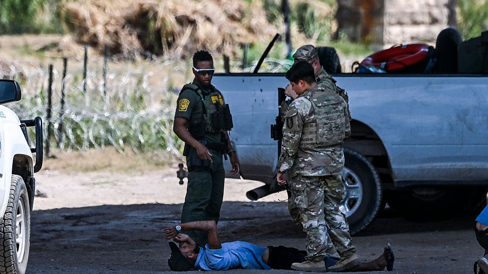 A man lies on the ground after being asked to sit as he and other migrants are apprehended by U.S. Border Patrol and National Guard troops near the border with Mexico in Eagle Pass, Texas, the U.S., June 30, 2022. /CFP