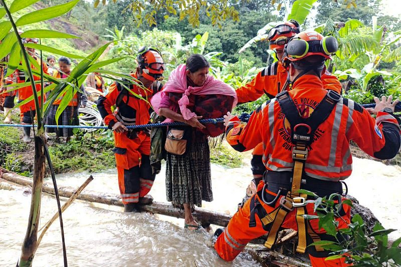 Volunteer firefighters evacuate people after being trapped in a landslide, following the passage of Tropical Storm Julia, at Queja village, in San Cristobal Verapaz, Guatemala, October 10, 2022. /CFP