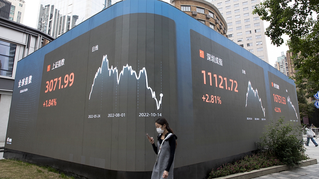 A woman walks past in front of an electric monitor displaying stock Indexes in Shanghai, China, October 14, 2022. /CFP