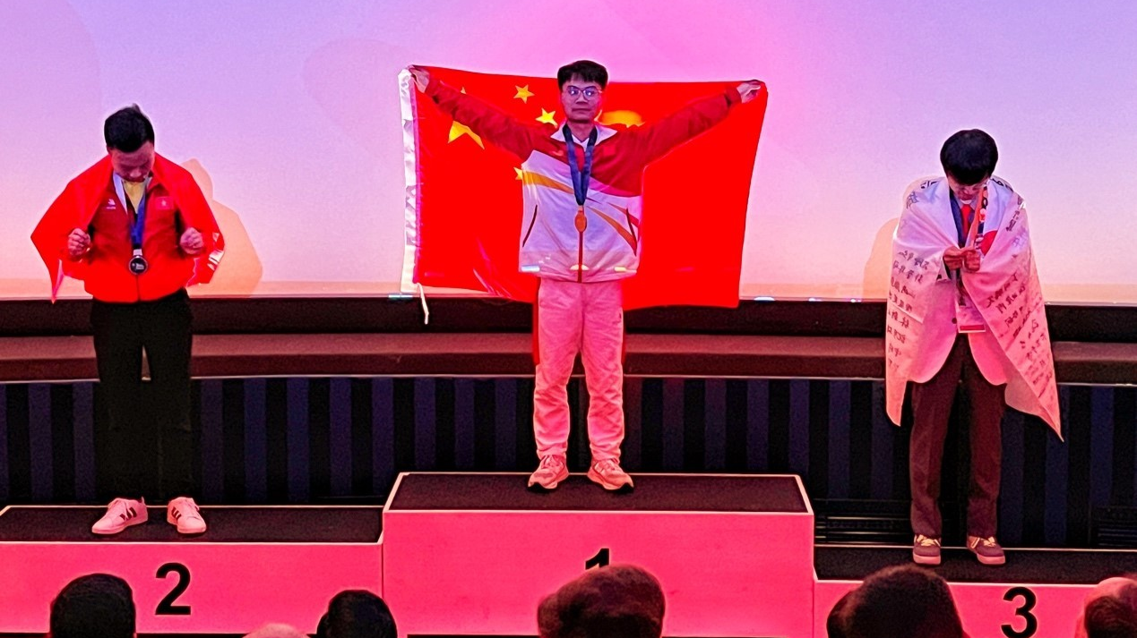 China's Zhou Chujie holds the national flag high after winning the gold medal in computer numerical control milling at the WorldSkills Competition 2022 Special Edition in Germany, October 16, 2022. /CMG