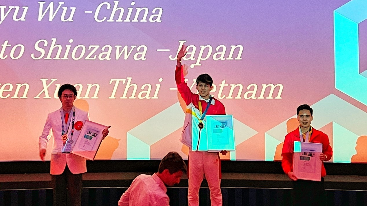 Chinese competitor Wu Hongyu motions to the audience from atop the podium after winning the gold medal in CNC turning at the WorldSkills Competition 2022 Special Edition in Leonberg, Germany, October 16, 2022. /CMG