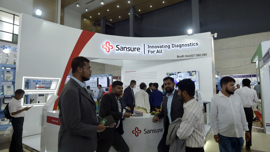 Visitors talk in front of an exhibition booth of Sansure Biotech Inc. during the 