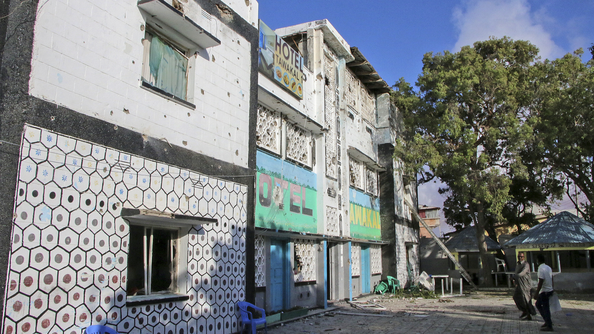 People walk next to the damaged Tawakal hotel after it was attacked in the port city of Kismayo, southern Somalia, October 24, 2022. /CFP