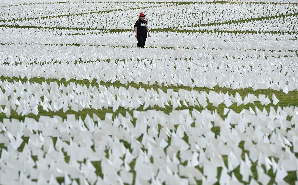 A woman walks through a field of white flags honoring the lives lost to COVID-19 on the National Mall in Washington, D.C., U.S., September 16, 2021. /CFP