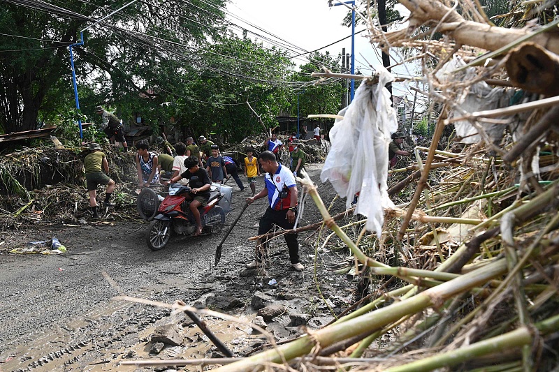 Motorists and pedestrians pass a pile of debris on the side of a road in Noveleta Town, Cavite Province, Philippines, October 31, 2022. /CFP
