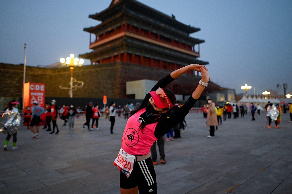 A runner stretches to warm up before the Beijing Marathon in Beijing, China, November 6, 2022. /CFP
