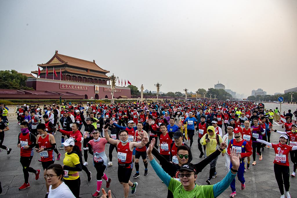Runners wave to a camera during the Beijing Marathon in Beijing, China, November 6, 2022. /CFP