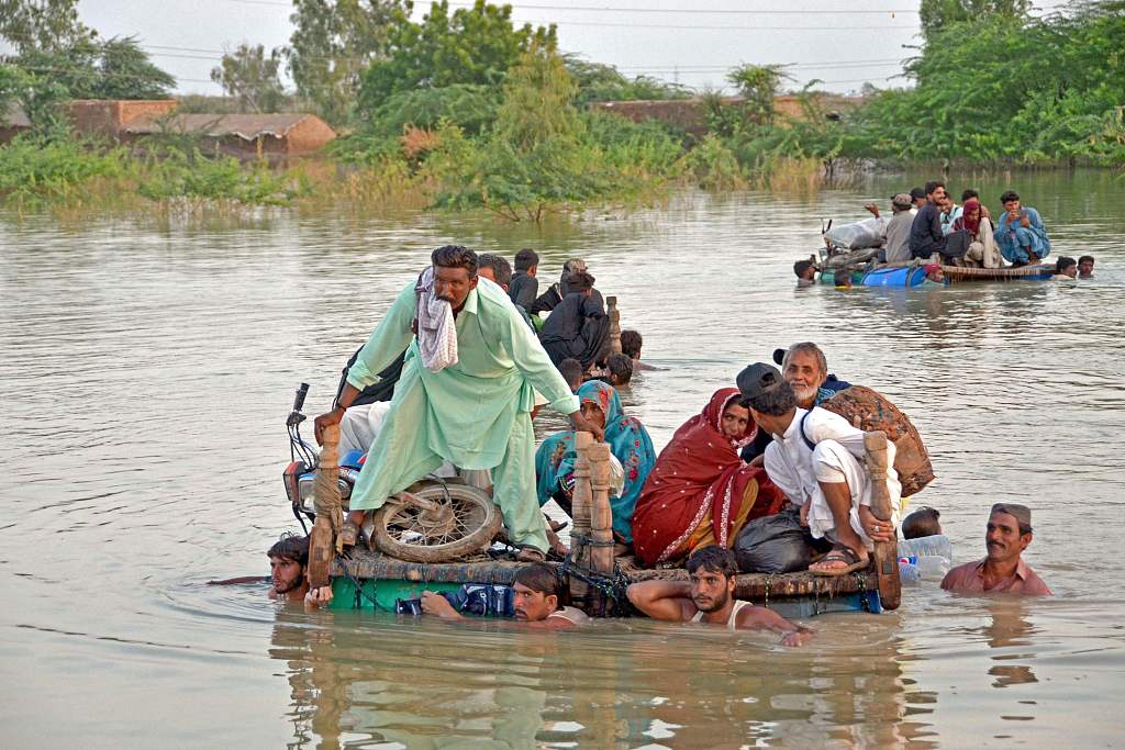 Displaced people wade through floodwater after heavy monsoon rains in Jaffarabad district in Balochistan Province of Pakistan on September 8, 2022. The death toll from the cataclysmic floods in the country exceeded 1,700. /VCG
