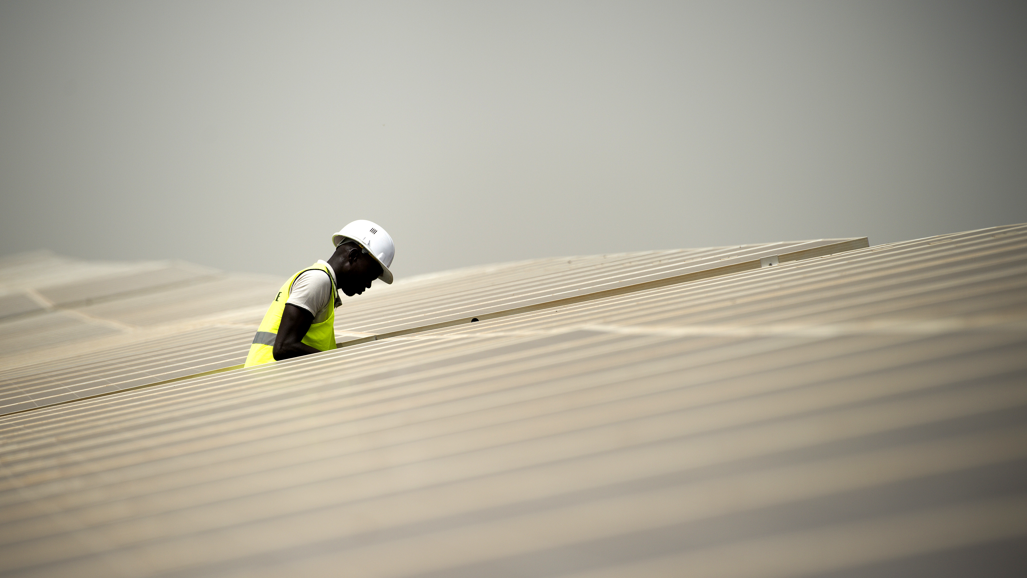 A worker inspects photovoltaic solar panels in an array at the Senergy Santhiou Mekhe PV solar plant in Thies, Senegal. /Getty