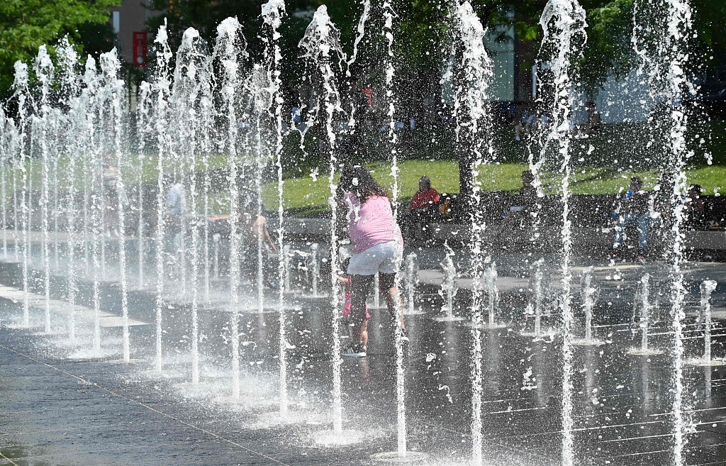 A woman helped a little girl walk between a water fountain during a heatwave at the Place des Arts in Montreal, Quebec, June 21, 2020 as temperatures reached 33 degrees Celsius. /CFP