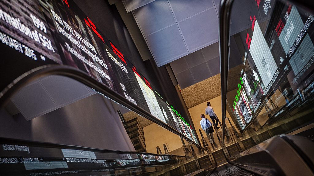 Pedestrians exit an escalator at the Singapore Exchange headquarters in Singapore, January 21, 2015. /CFP
