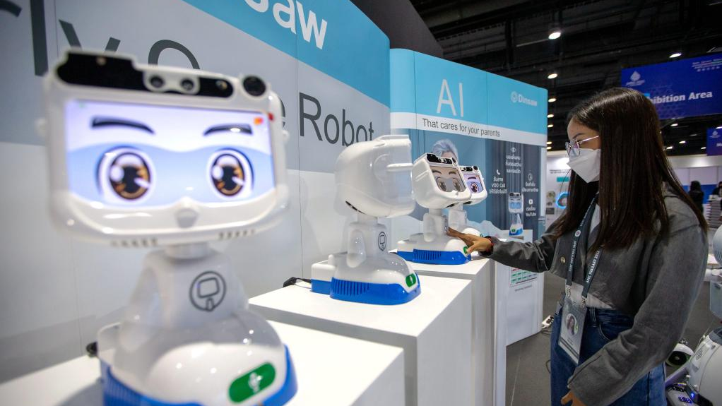 A staff member interacts with a robot at the media center of APEC 2022 in Bangkok, Thailand, Nov. 14, 2022. The 29th Asia-Pacific Economic Cooperation (APEC) Economic Leaders' Meeting will be held in Bangkok, Thailand, on Nov. 18-19. /Xinhua