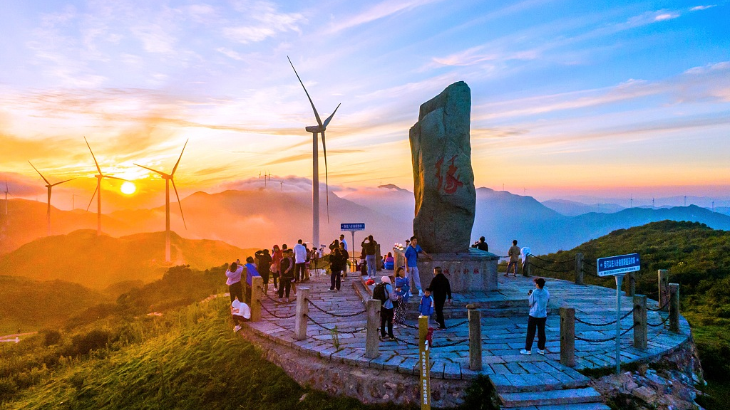 Tourists take photos of the sunrise and wind turbines at the mountain ridge of Baguanao Scenic Area in Shicheng County, east China's Jiangxi Province, August 30, 2022. /CFP
