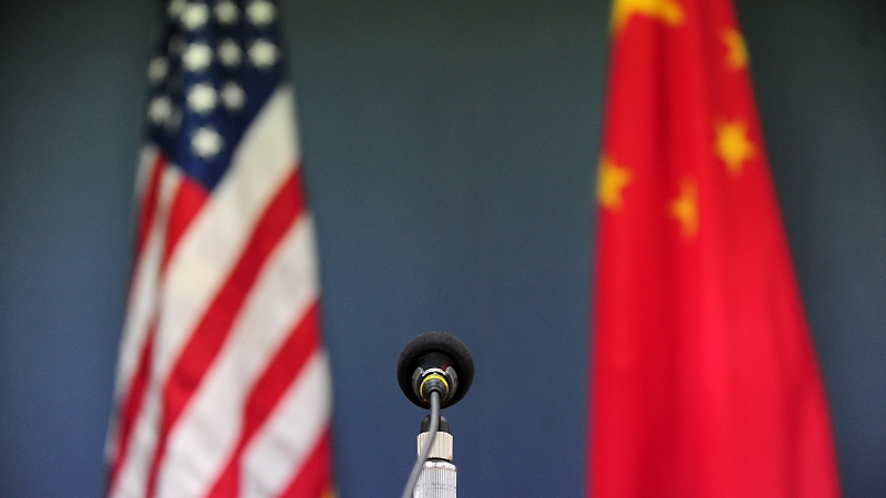 A microphone stands in front of the national flags of the U.S. and China. /CFP