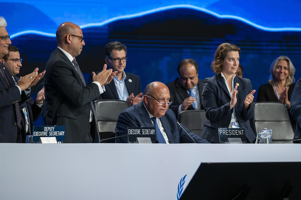 Sameh Shoukry(M), foreign minister of Egypt and the COP27 President, sits while the surrounding participants clap during the closing ceremony at the COP27 UN climate summit. /VCG