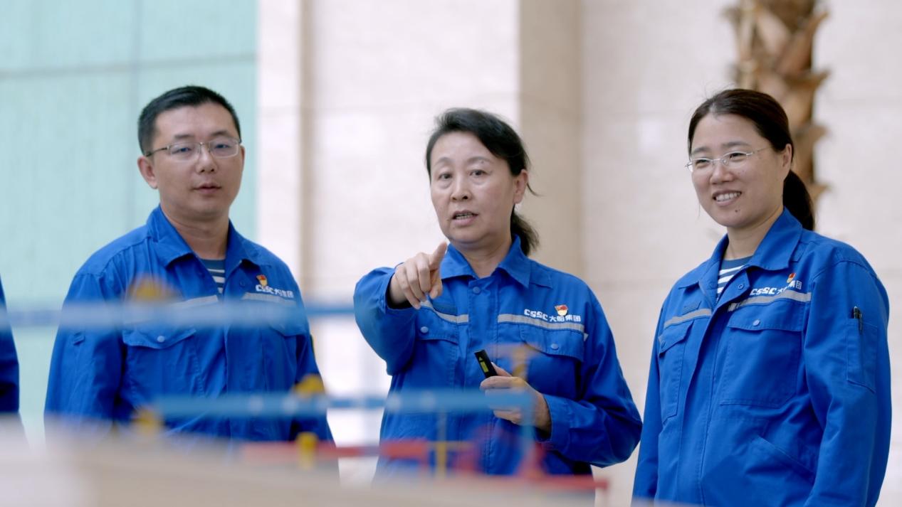 Guan Yinghua (C), deputy chief engineer of Dalian Shipyard, talks with her colleagues. /CGTN