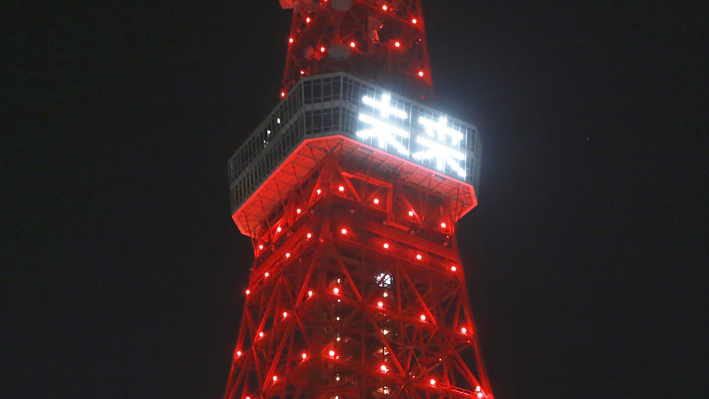 The Tokyo Tower is illuminated in red and with a display of characters read 