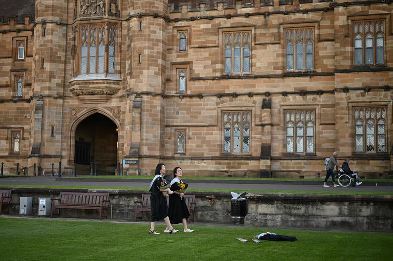 2020 年 7 月 4 日，澳大利亚悉尼，在 COVID-19 爆发期间取消了现场毕业典礼后，两名中国国际学生穿着毕业礼服在他们攻读硕士学位的悉尼大学校园内拍照./路透社