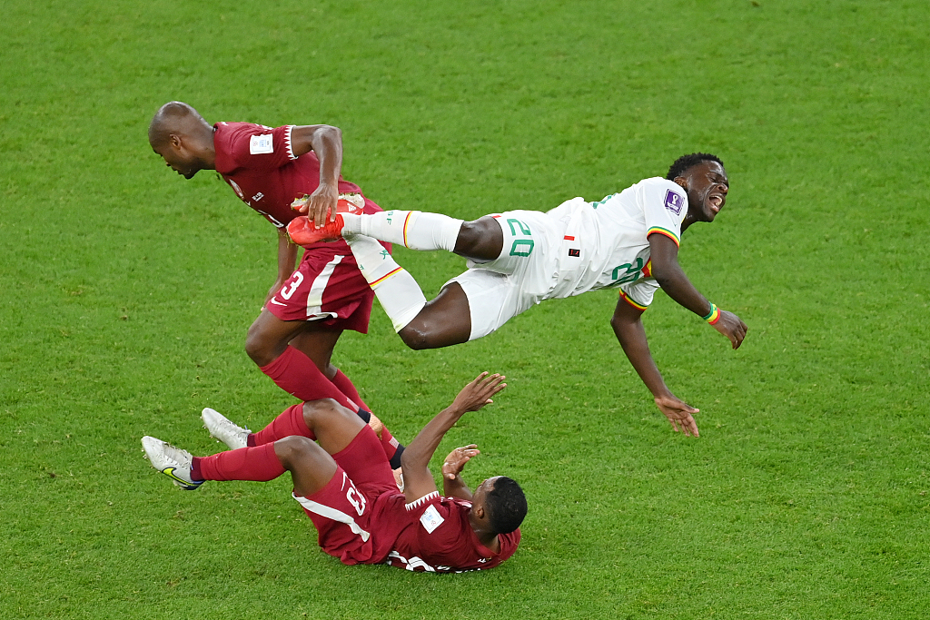 Bamba Dieng (#20) of Senegal is challenged by Abdelkarim Hassan and Assim Madibo of Qatar during their World Cup clash at Al Thumama Stadium in Doha, Qatar, November 25, 2022. /CFP