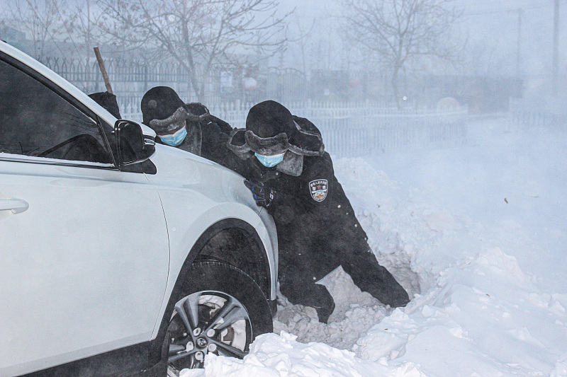 Local police help push a car backward from the heavy snow in Altay, northwest China's Xinjiang Uygur Autonomous Region, November 26, 2022. /CFP