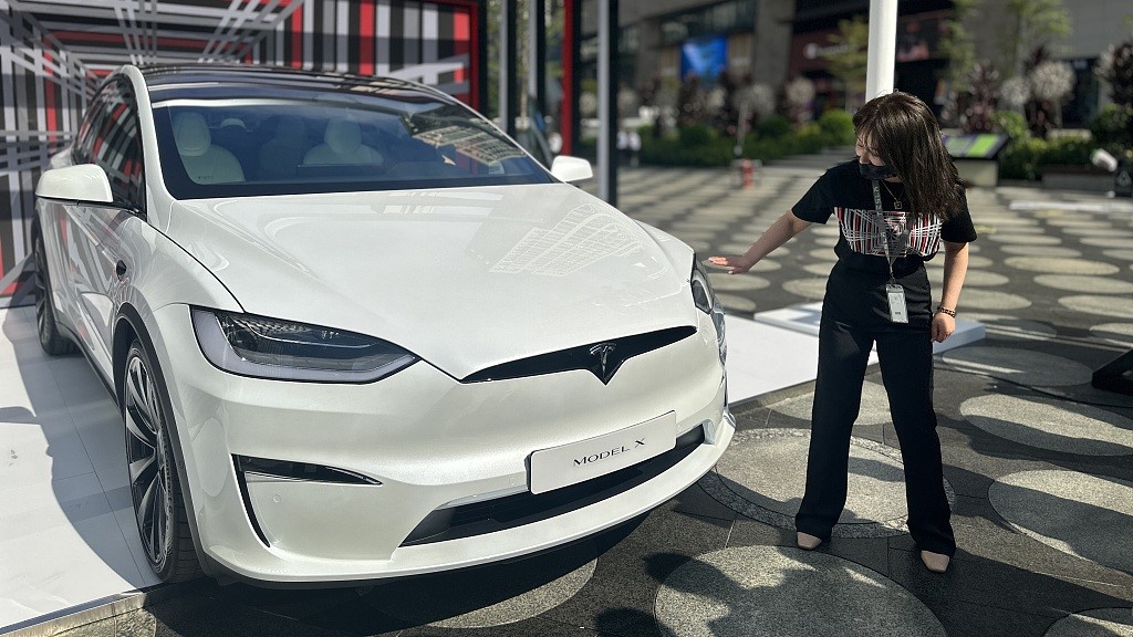 A woman stands by a Tesla model X in Shenzhen, China, November 17, 2022. /CFP