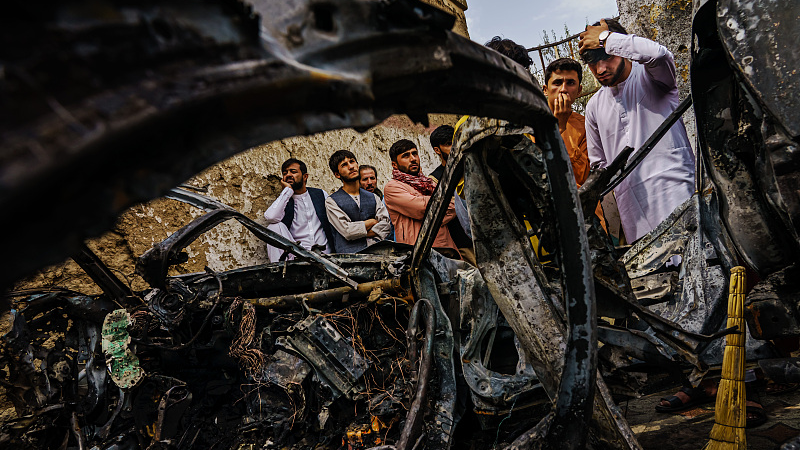 Relatives and neighbors of the Ahmadi family gathered around the incinerated husk of a vehicle targeted and hit by an American drone strike, which killed 10 people including children, in Kabul, Afghanistan, August 30, 2021. /CFP