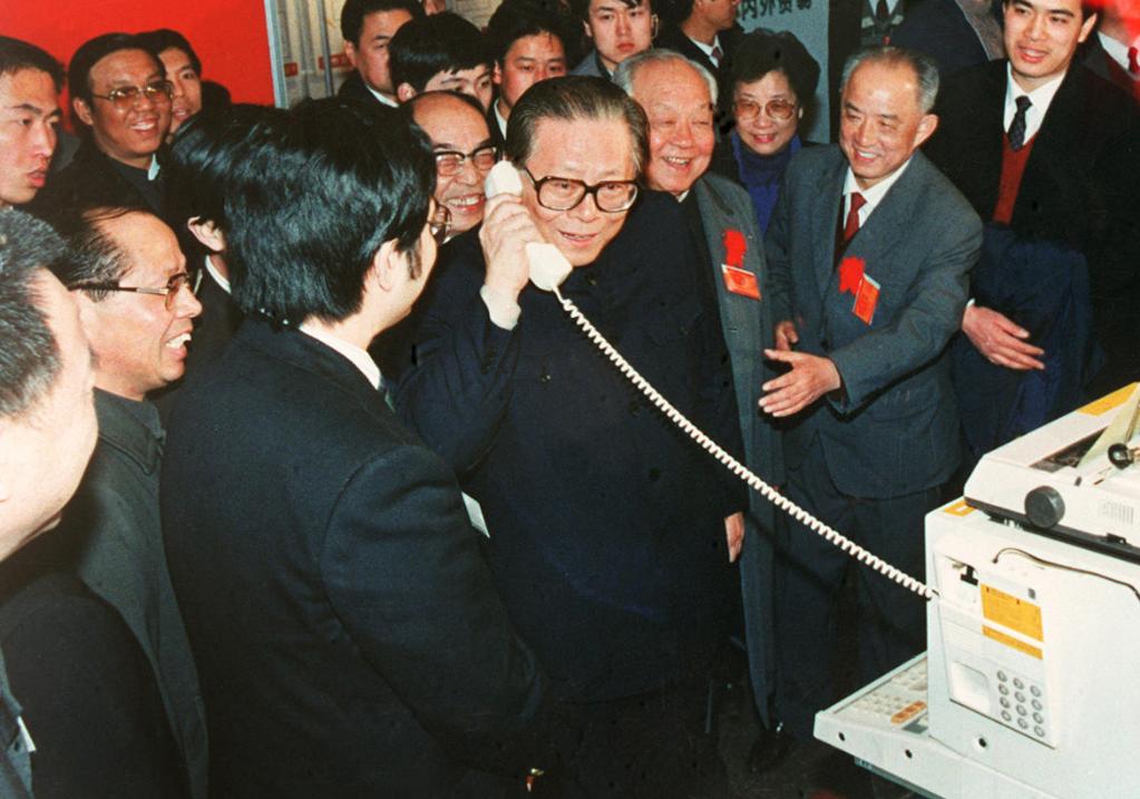 Jiang Zemin tries out an international call to greet workers while visiting the Beijing Exhibition Hall, May 1984. New electronics products were showcased at the event. /Xinhua