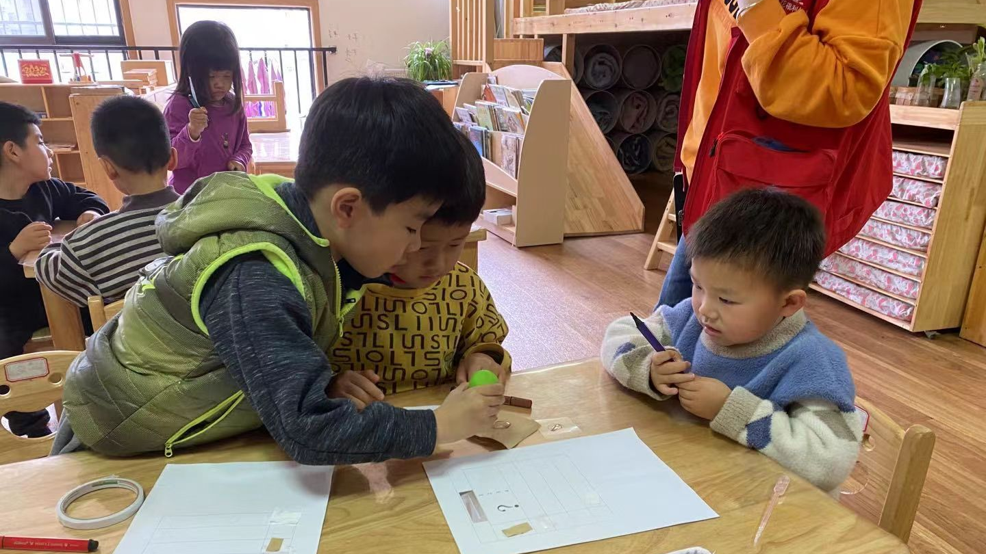 Guoguo helps a boy apply glue at Qisehua Kindergarten, Zhengzhou, Henan Province, China, 2022. /courtesy of Fu Jie