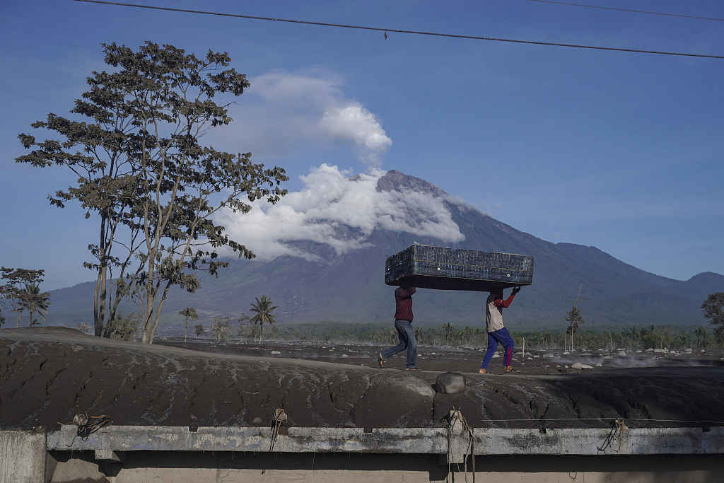 People collect items from houses affected by the eruption of Mount Semeru, holding a mattress and preparing to take it to a temporary shelter in Lumajan, East Java, Indonesia, December 6, 2022. /CFP