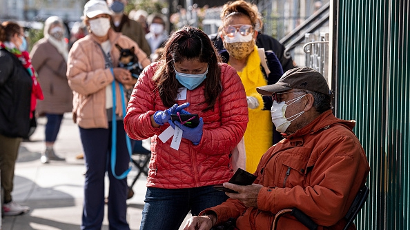People wearing protective masks wait in line to receive a dose of the Moderna COVID-19 vaccine at a walk-up vaccination site in San Francisco, California, U.S., February 3, 2021. /Getty