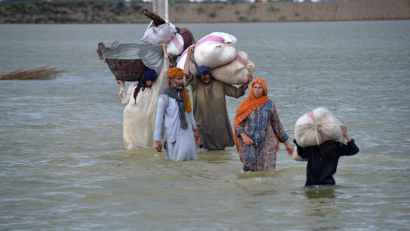 A displaced family wades through a flooded area after heavy rainfall, in Jaffarabad, Pakistan, August 24, 2022. /CFP