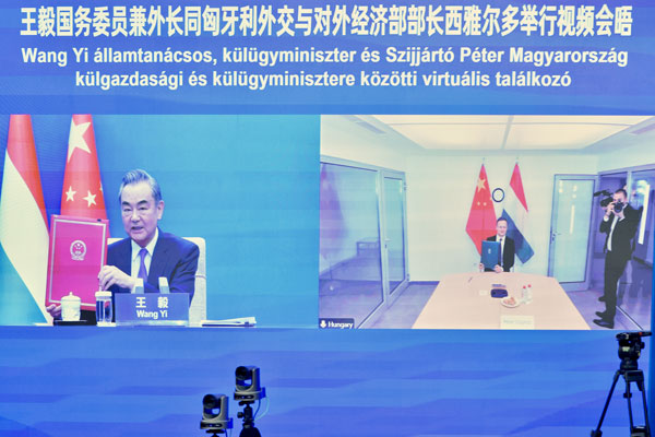 Wang Yi (L) and Hungarian Foreign Minister Peter Szijjarto co-sign an agreement via video, December 13, 2022. /Chinese Foreign Ministry