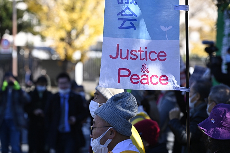 People gather outside the Japanese Prime Minister Fumio Kishida's office while holding placards denouncing the violation of Article 9 of the Japanese Constitution in Tokyo, Japan, December 16, 2022. /CFP