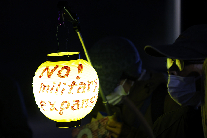 A protester holds a lantern during a demonstration against the Japanese government's extension of the defense budget in Tokyo, Japan, December 15, 2022. /CFP