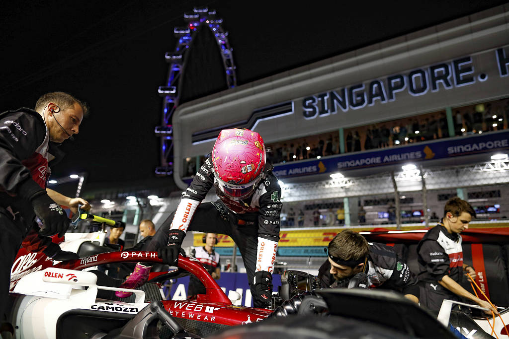 Zhou Guanyu gets into his Alfa Romeo race car prior to the street race at night at Marina Bay Street Circuit in Singapore, October 2, 2022. /CFP
