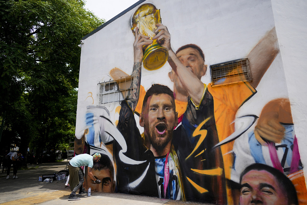 An artist paints a mural featuring Argentine star Lionel Messi holding up the World Cup trophy in Buenos Aires, Argentina, December 22, 2022. /CFP