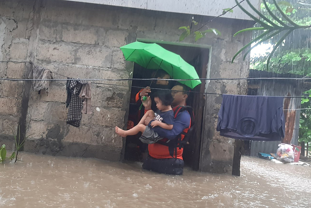 Rescuers evacuate a child from a flooded area  in Ozamian, Philippines, December 25, 2022. /CFP