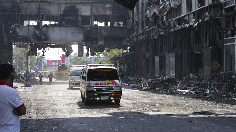 Thai ambulances drive through a ruined building as they head back toward Thailand border at the scene of a massive fire at a Cambodian hotel casino in Poipet, west of Phnom Penh, Cambodia, December 30, 2022. /CFP