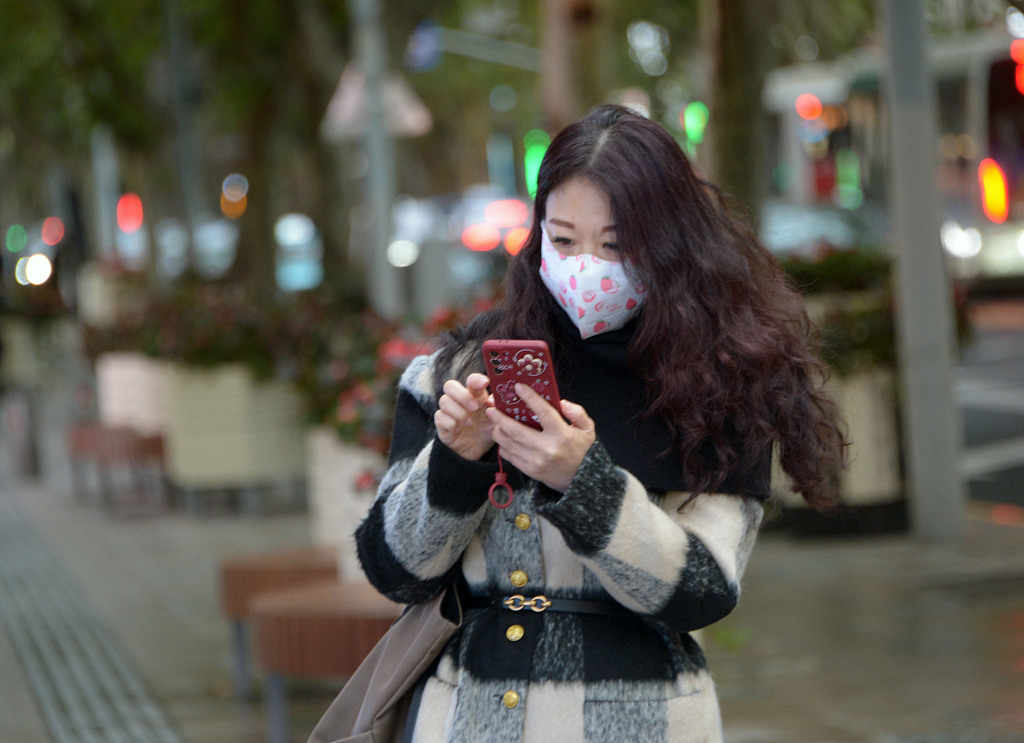 A woman scans her mobile phone at a street in Shanghai, China, December 4, 2022. /CFP