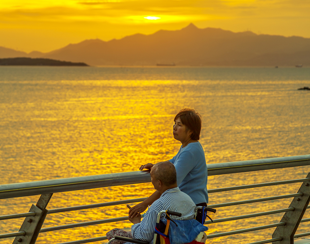 A middle-aged woman takes an elderly patient to watch the sunset in Shenzhen, China, July 25, 2020. /CFP