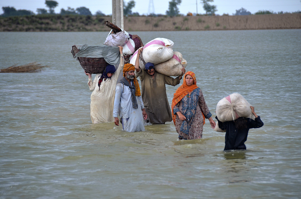 A displaced family wades through a flooded area after heavy rainfall flooded Jaffarabad, a district of Pakistan's southwestern Baluchistan province, on Aug 24, 2022. In Pakistan's devastating flooding, over 1/3 of the country was under water. /VCG